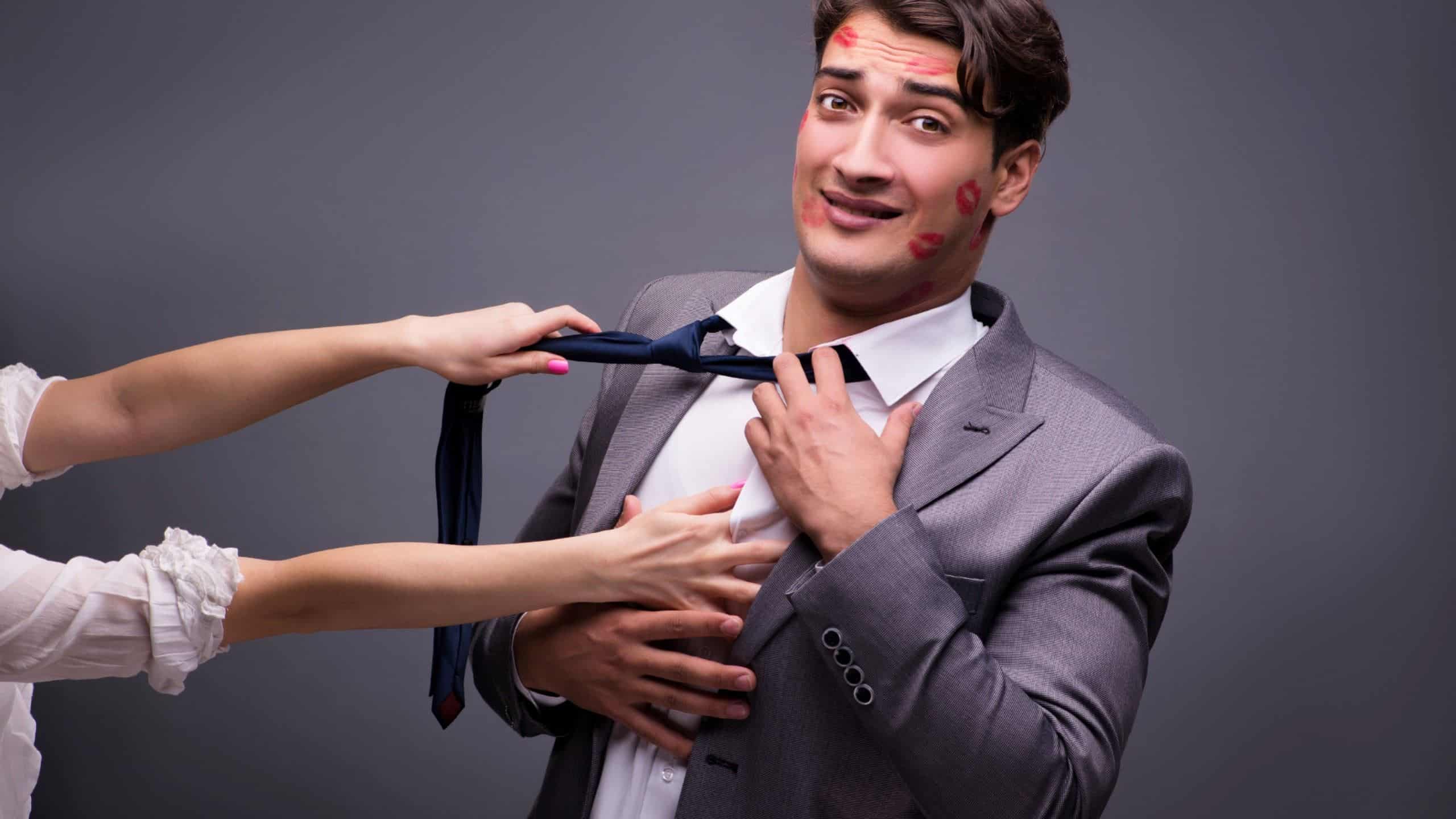 A man covered in lipstick kisses being pulled towards a woman.