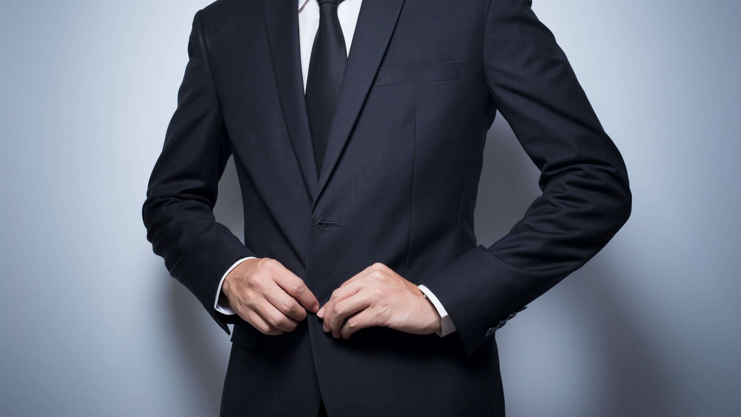 A man in a black suit with a black tie.