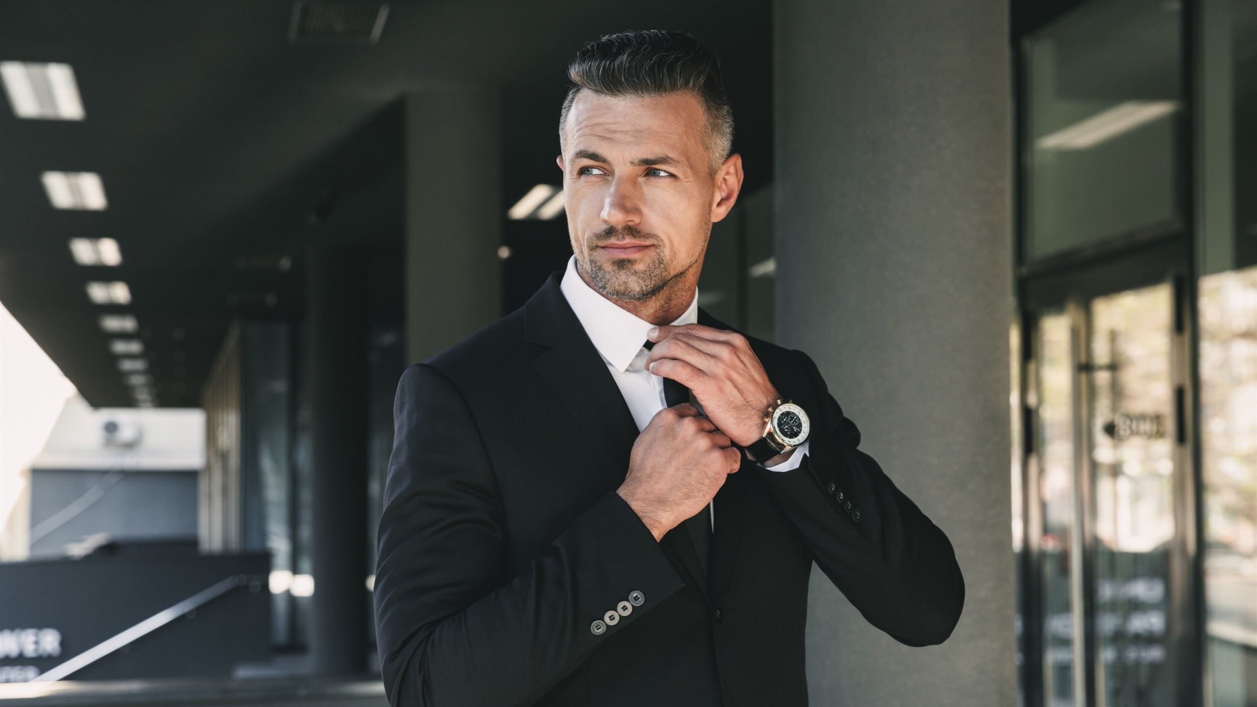 A well dressed man straightening his tie.