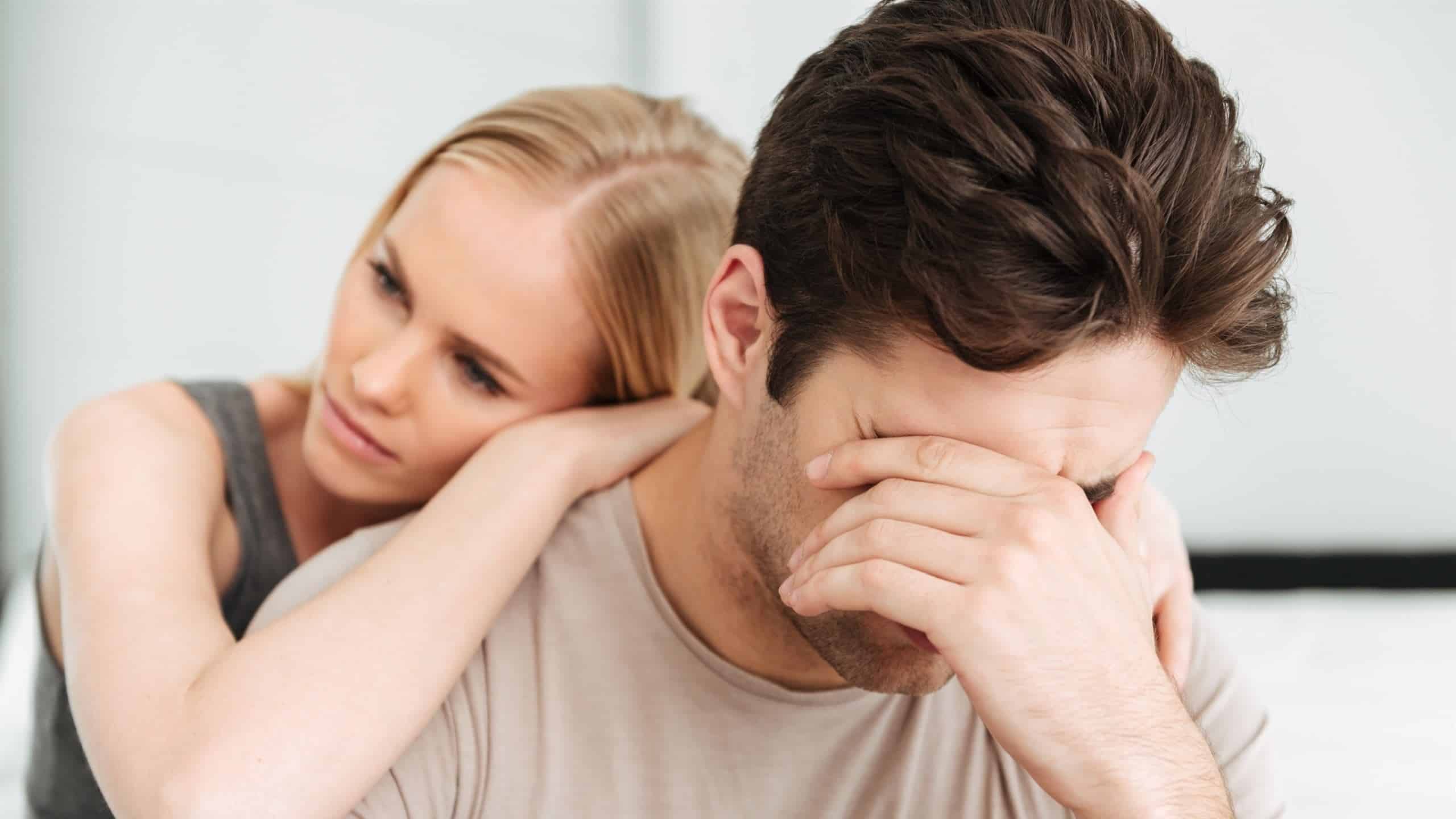 A sad man crying while his girlfriend comforts him.