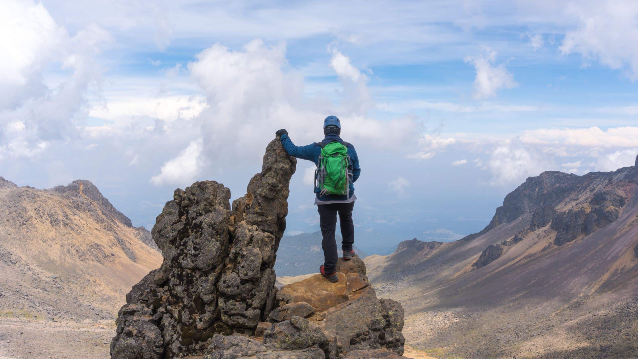 A man standing on the tip of the mountain and admiring the view.