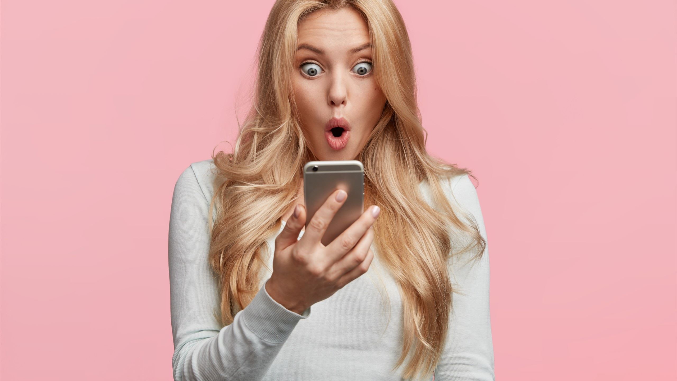 A bold, attractive girl looking very surprised at her mobile phone.